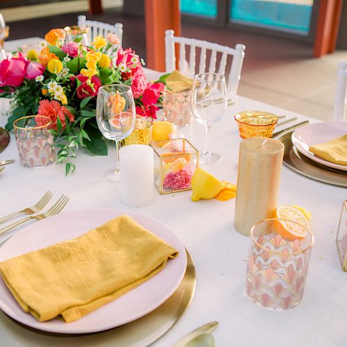 A beautifully set table with yellow napkins, floral centerpiece, candles, and decorative glasses, ready for a festive meal.