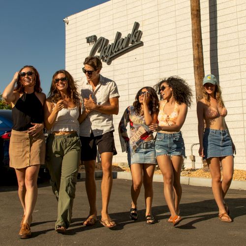 A group of people walks and smiles together outside a building with 