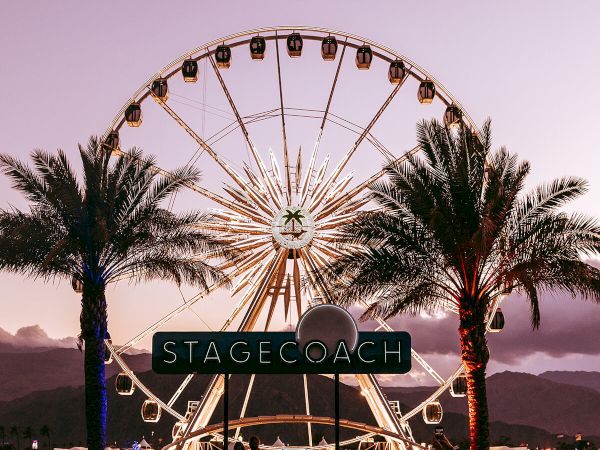 The image shows a Ferris wheel at sunset, framed by palm trees, with a crowd below and a sign reading "STAGECOACH."